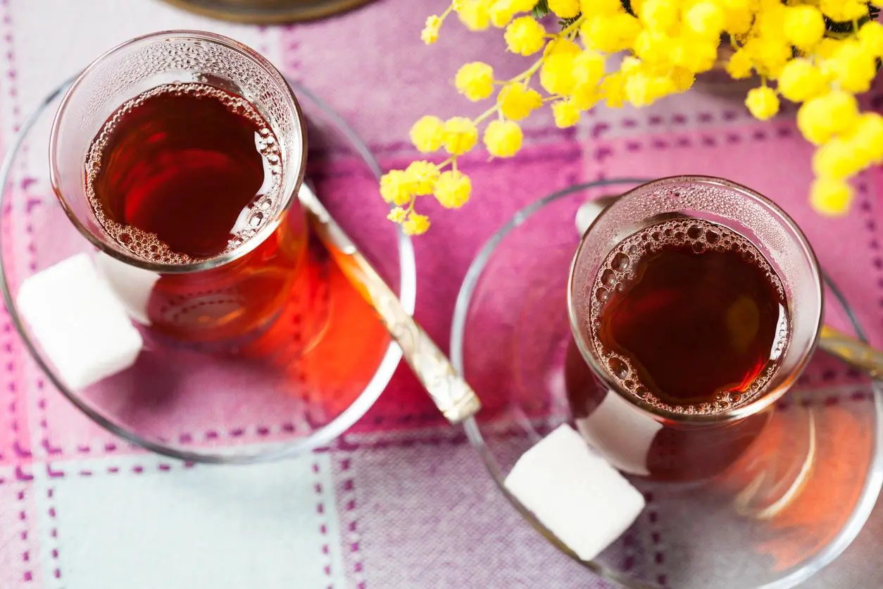 Two cups of tea with sugar cubes.