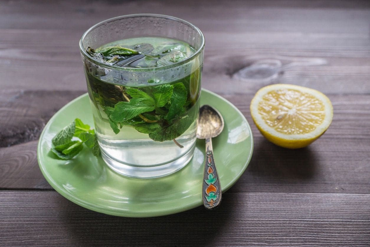 Mint tea with lemon on a green saucer.