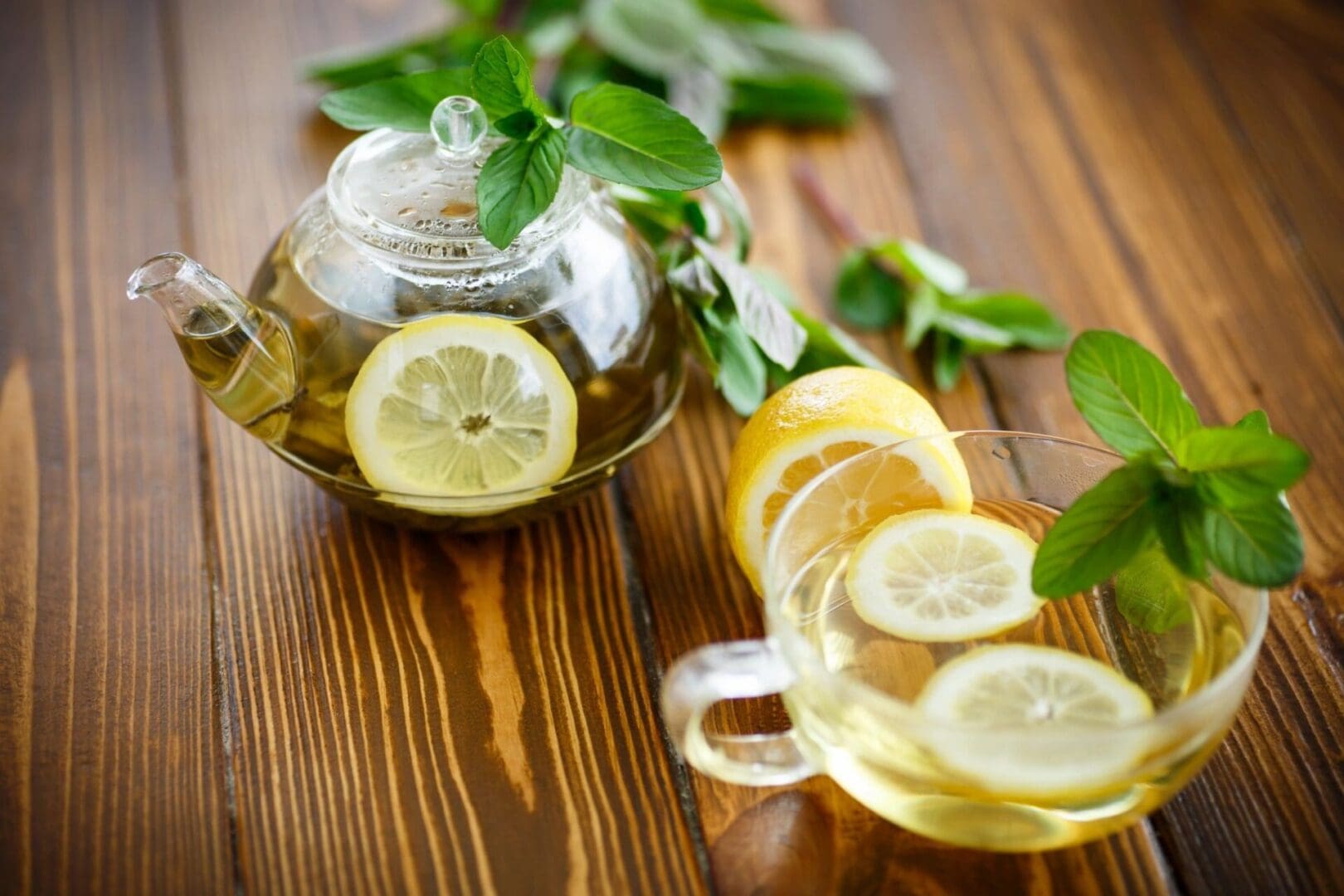 Lemon tea with mint in glass teapot and cup.