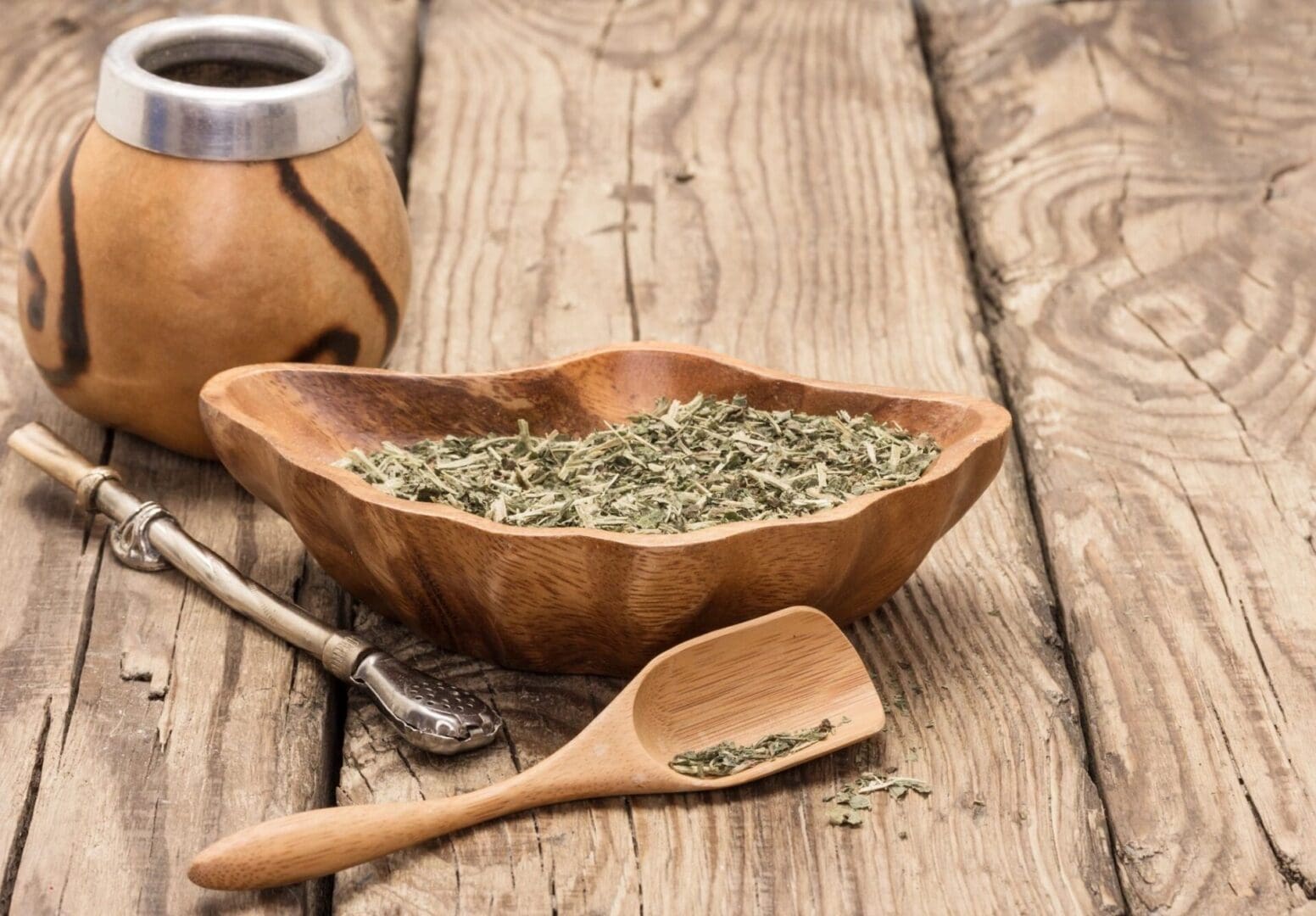 Yerba mate tea leaves in bowl and scoop.