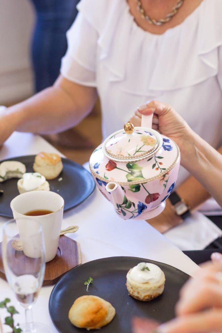 Floral teapot pouring tea at high tea.