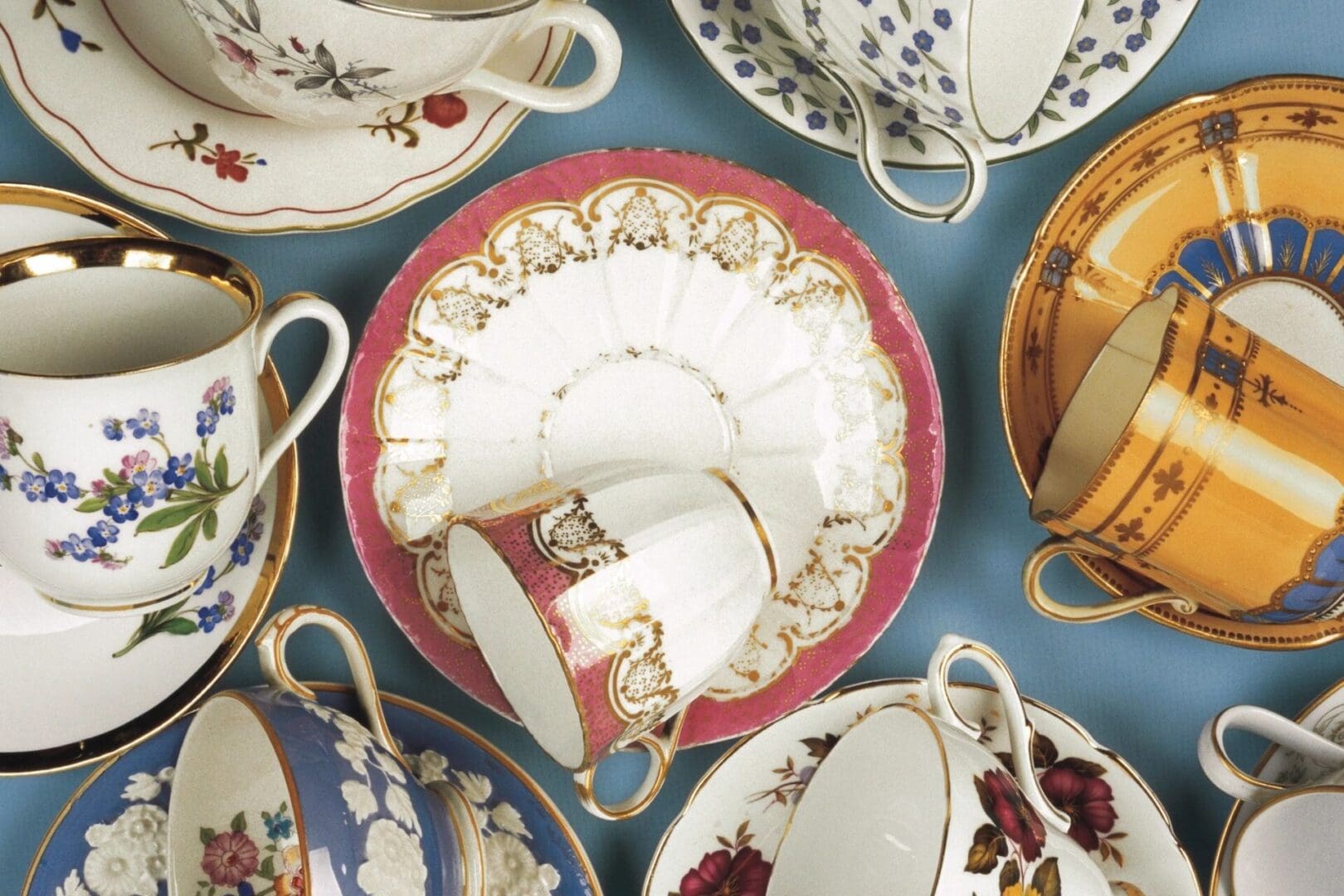 Porcelain teacups and saucers on blue background.