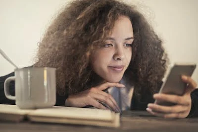 Woman with curly hair looking at phone.