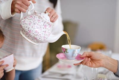 Woman pouring tea into a teacup.