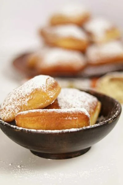 Powdered sugar donuts in a bowl.