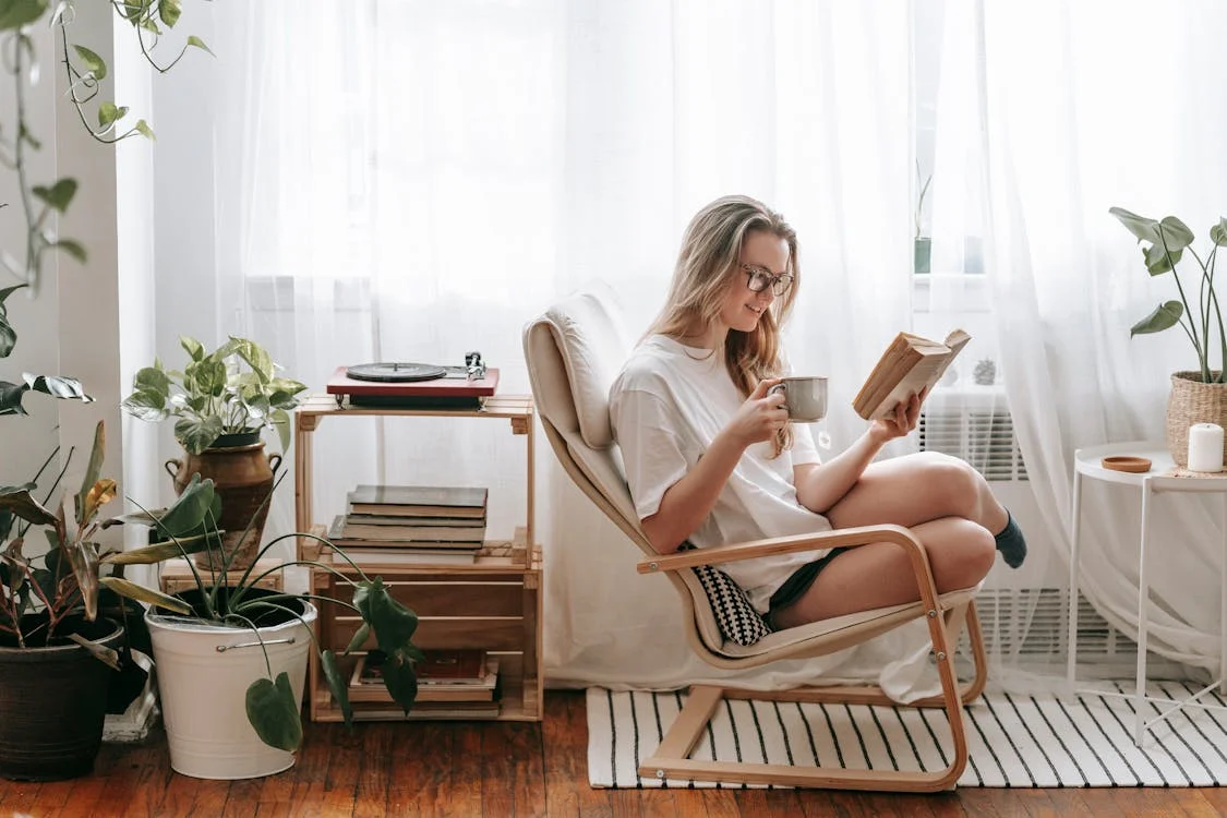 Woman reading a book in a chair.